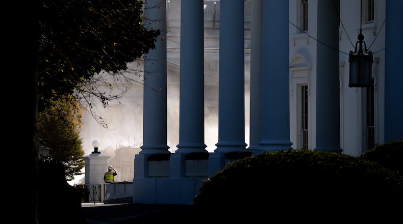 A construction worker watches through clouds of demolition dust as bulldozers bring down the walls of the East Wing of the White House on Thursday morning, Oct. 23, 2025. President Donald Trump initially said construction of his 90,000-square-foot ballroom would not dismantle parts of the White House. His officials now say it is cheaper and more structurally sound to simply demolish the East Wing.  (Doug Mills/The New York Times)