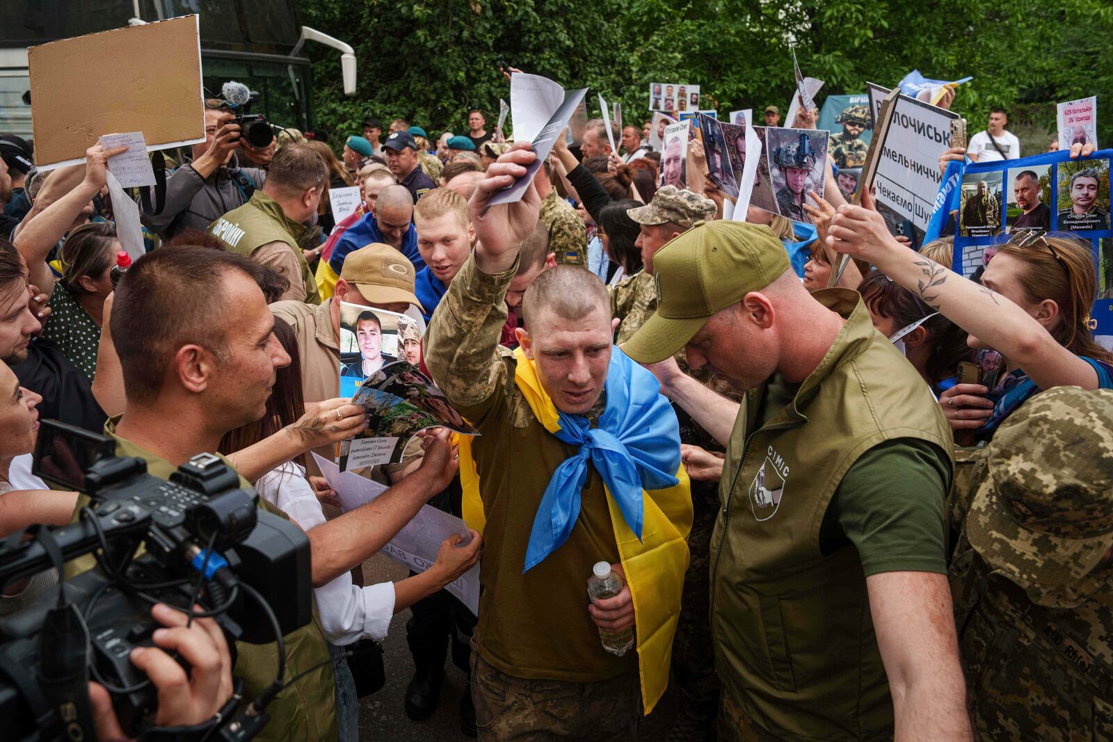 Ukrainian soldiers walk though human corridor with people holding photos of their missed relatives after returning from captivity after a POWs exchange between Russia and Ukraine, in Chernyhiv region, Ukraine, Monday, June 9, 2025. (AP Photo/Evgeniy Maloletka)