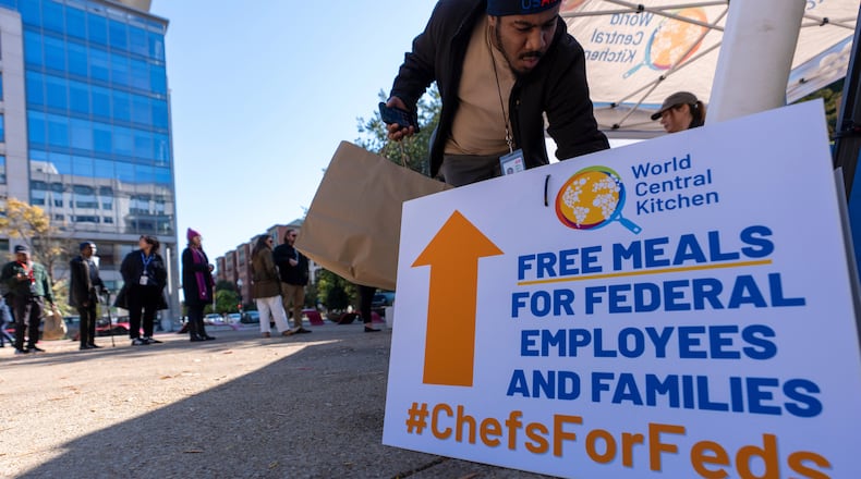 A person gets a bottle of water to go with a meal distributed by chef Jose Andres' World Central Kitchen for federal workers and their families in Canal Park, Monday, Oct. 27, 2025, in Washington. (AP Photo/Alex Brandon)