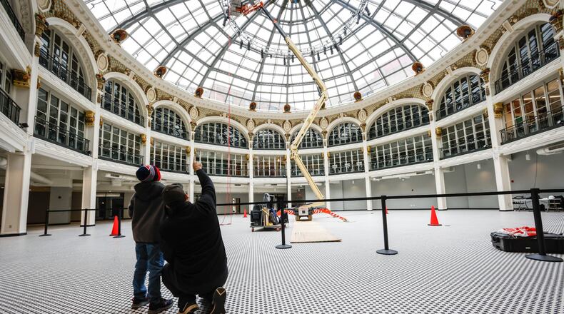 A father and son watch a worker put up lights at the Dayton Arcade on Thursday, Feb. 24, 2022. JIM NOELKER/STAFF