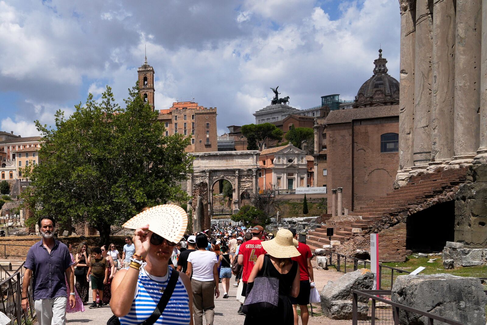 Tourists use use fans and sun hats as they visit the Forum in Rome on Tuesday, July 22, 2025. (AP Photo/Gregorio Borgia)