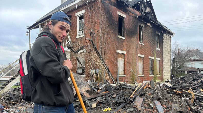 Jordan Trent, a 22-year-old homeless man, sifts through debris left over after a home on the 500 block of North Broadway Street burned down on March 8, 2023. Trent said he was in the home at the time of the fire and he thinks a couple of his friend might have been killed by the blaze. Dayton authorities recovered five bodies from the property after the fire. CORNELIUS FROLIK / STAFF
