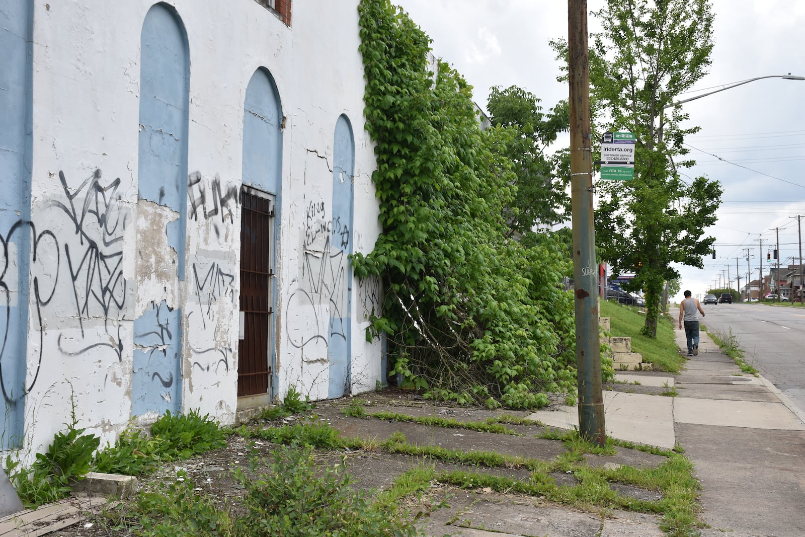 A man walks along North Main Street past vacant properties that are covered in graffiti. CORNELIUS FROLIK / STAFF