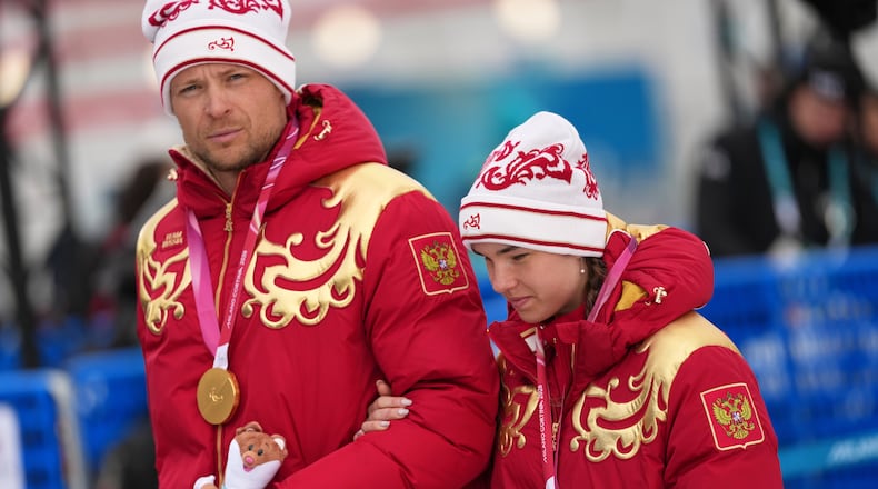 Anastasiia Bagiian, of Russia, leaves the podium with her guide Sergei Siniakin, after winning the gold medal in the cross country skiing women's 10Km interval start classic vision impaired final at the 2026 Winter Paralympics, in Tesero, Italy, Wednesday, March 11, 2026. (AP Photo/Evgeniy Maloletka)