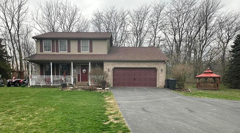 The front of home has an asphalt driveway that leads to a two-car attached garage. The house has a covered front porch with railings. CONTRIBUTED PHOTOS