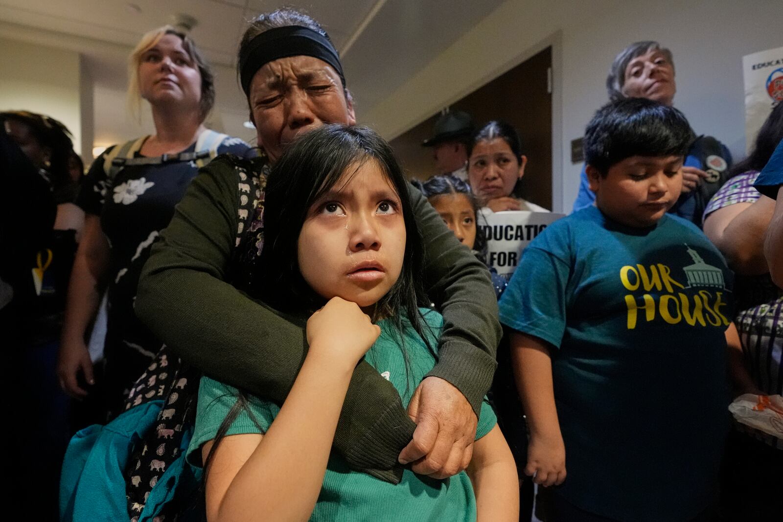 FILE - A woman embraces her child outside a House hearing room during protests against a bill that would allow public and charter schools to deny immigrant students from enrolling for classes in Nashville, Tenn., March 11, 2025. (AP Photo/George Walker IV, File)