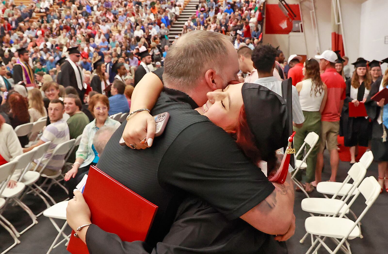 Wittenberg University graduate Olivia Washington hugs her father, Craig, following the 2023 Commencement Ceremony in Pam Evans Smith Arena. Weather forced the ceremony inside instead of the traditional Graduation Hollow but the rain couldn't dampen the celebration Saturday, May 13, 2023. BILL LACKEY/STAFF
