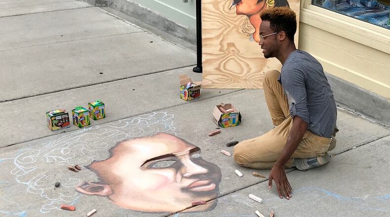 Dayton-based chalk artist Boy Blue uses chalk to create a piece of art along North Fountain Avenue in Springfield on Friday afternoon. Boy Blue will also be creating another piece of chalk art at Saturday’s Chalktoberfest being held in downtown Springfield. Michael Cooper/Staff