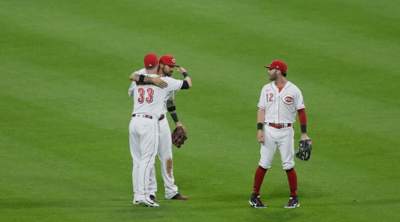 Jesse Winker, left, gets a hug from Nick Castellanos as the Reds celebrate a victory against the Brewers on Friday, May 21, 2021, at Great American Ball Park in Cincinnati. David Jablonski/Staff