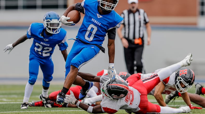 Dunbar High School junior Ulysses Porter runs past Cincinnati Hughes sophomore Devon Brown during their game on Thursday, Aug. 21 at Welcome Stadium. The Big Red won 20-0. MICHAEL COOPER / STAFF