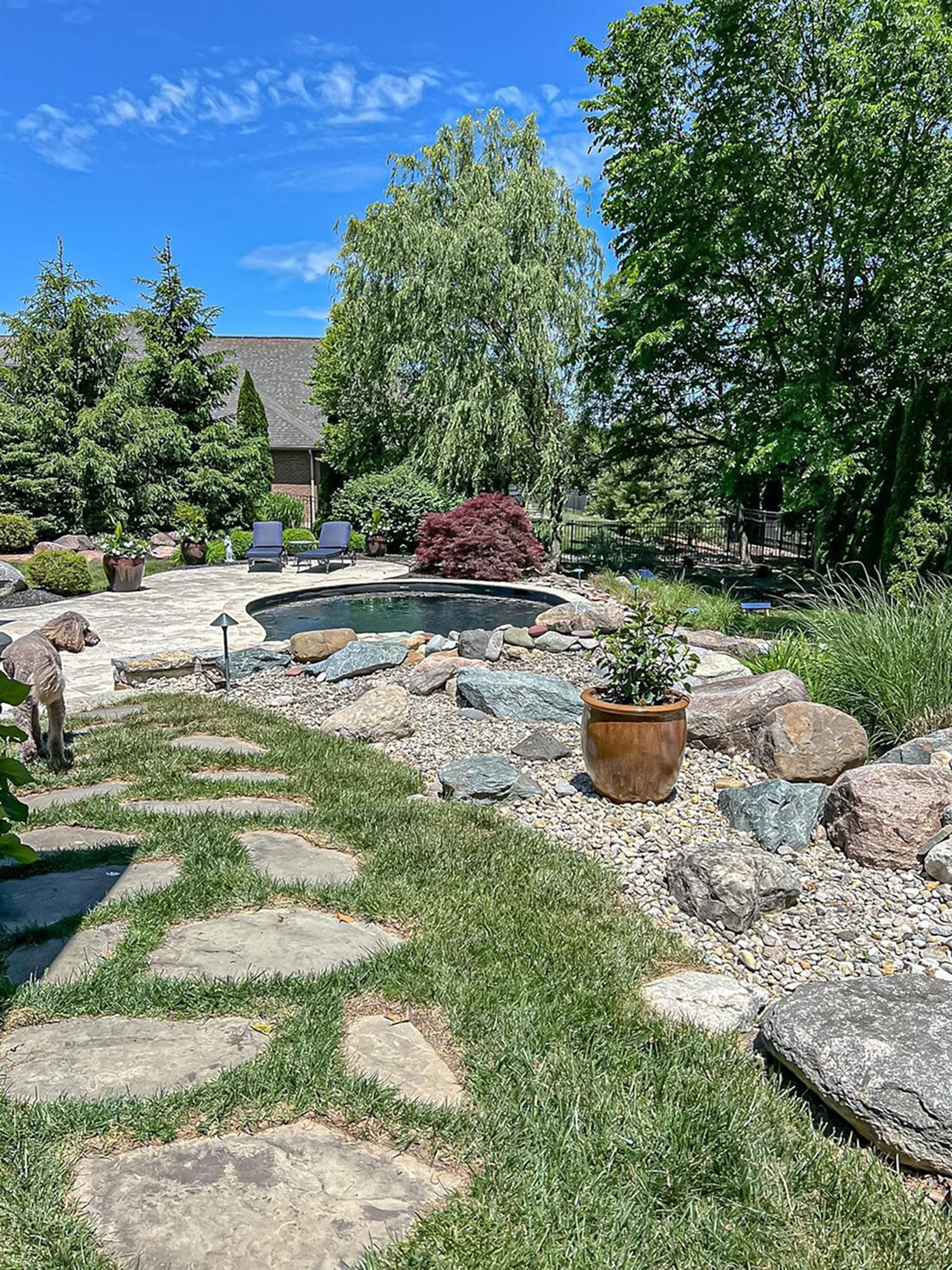 The inground pool is surrounded by professional hardscaping and landscaping. It has a waterfall feature and pavers surrounding it. CONTRIBUTED