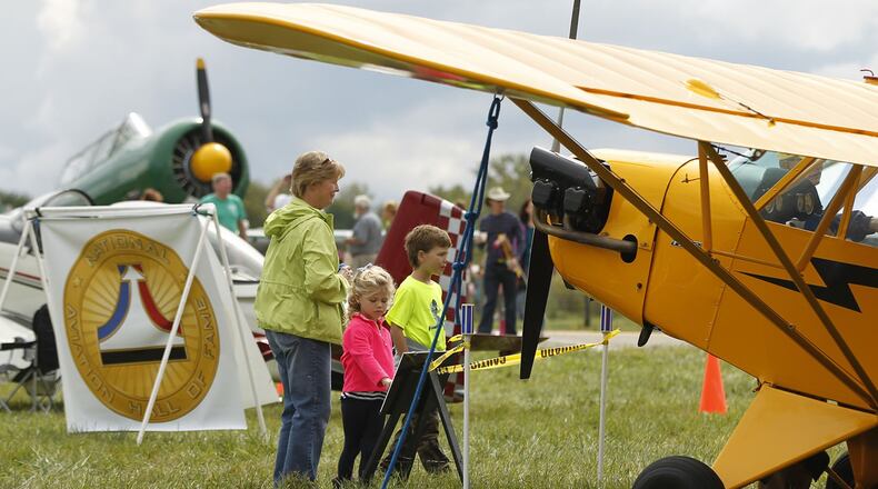 In this 2015 file photo, Brother and sister Mallory and Jack Behm, from Springboro, look at airplanes with their grandmother, Marilyn Bohardt, at the Great Wright Brothers Aero Carnival on Huffman Prairie. The event was hosted by the Dayton Aviation Heritage National Historical Park and included aircraft from the 1930’s including North American T-6, left, and the Piper Cub at right. Other period activities included a sheep-herding demonstration and propeller shaping by hand. TY GREENLEES / STAFF FILE PHOTO