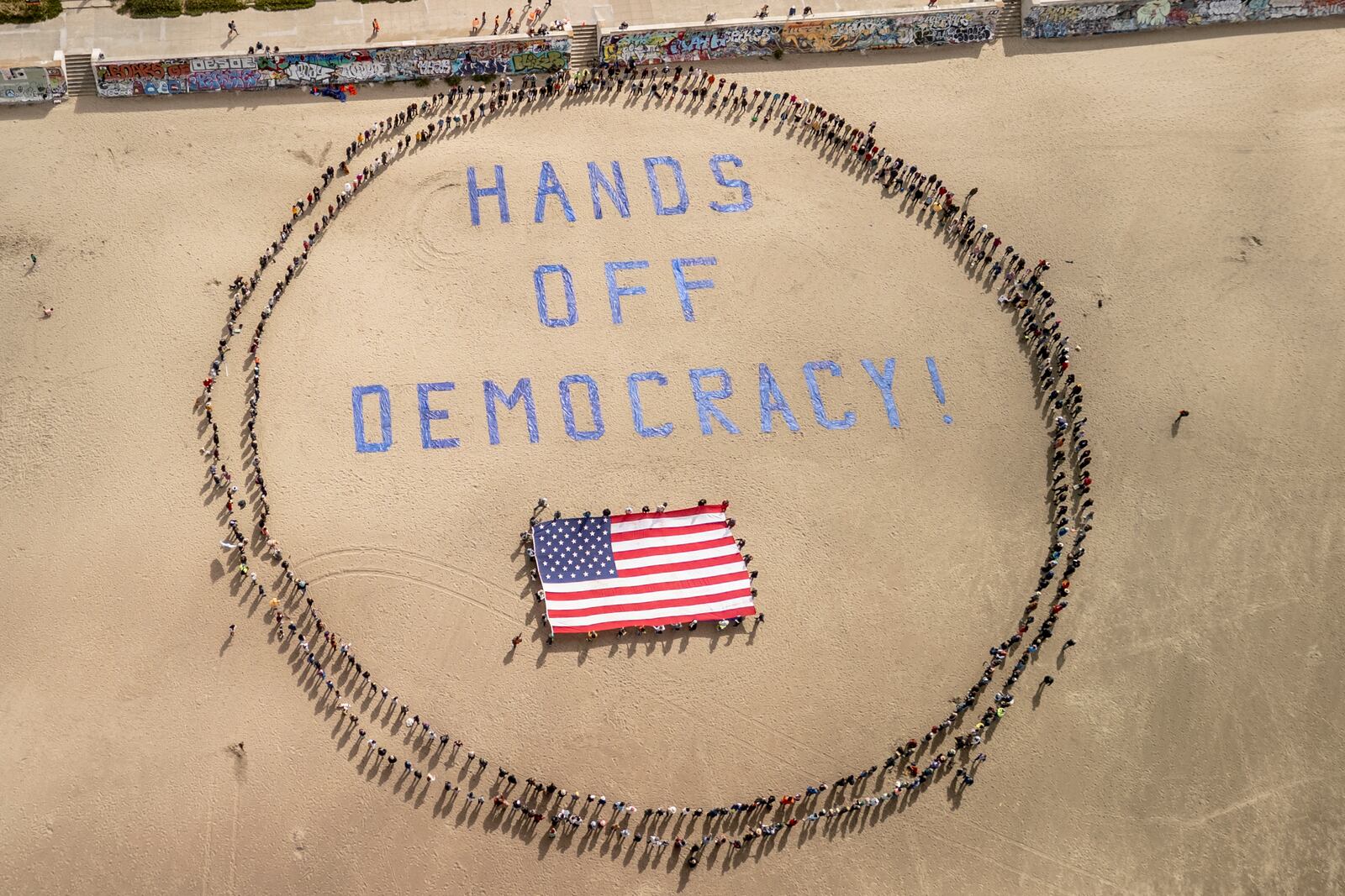 Protesters form a human banner on Ocean Beach during a protest against President Donald Trump, part of the "Hands Off" rallies held nationwide, in San Francisco, Saturday, April 5, 2025./San Francisco Chronicle via AP)
