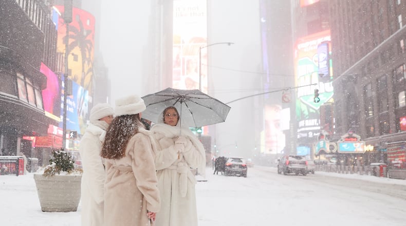 People wait to cross the street in Times Square during a winter storm, Sunday, Jan. 25, 2026, in New York. (AP Photo/Heather Khalifa)