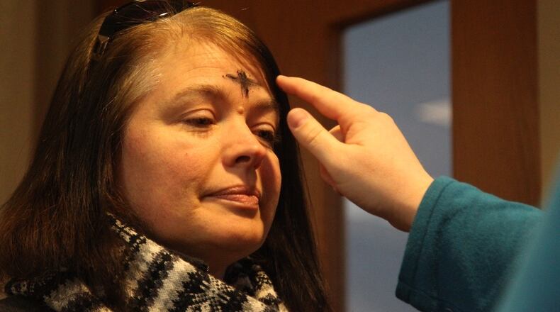 A woman receives ashes in the shape of a cross on her forehead during the Ash Wednesday ashes-to-go event at David’s United Church of Christ in Kettering. Weather forced the annual drive-through event inside. Jim Noelker / 2016 Staff File