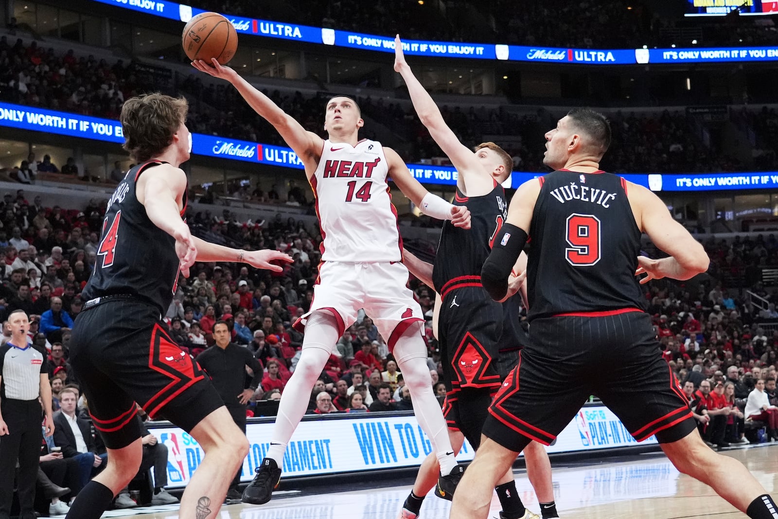 Miami Heat guard Tyler Herro (14) drives to the basket against Chicago Bulls forward Matas Buzelis, left, guard Kevin Huerter and center Nikola Vucevic, right, during the first half of an NBA play-in tournament basketball game in Chicago, Wednesday, April 16, 2025. (AP Photo/Nam Y. Huh)