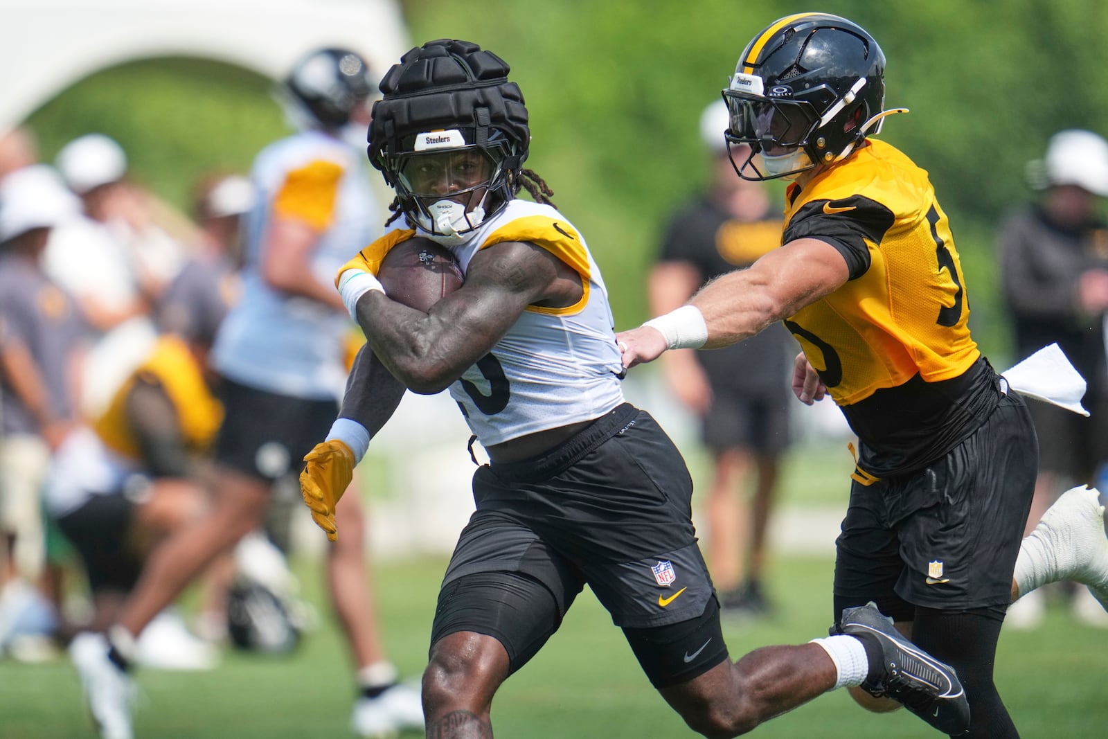 Pittsburgh Steelers running back Kaleb Johnson, left, breaks away from defender Cole Holcomb during practice at the team's NFL football training camp in Latrobe, Pa., Saturday, July 26, 2025. (AP Photo/Gene J. Puskar)
