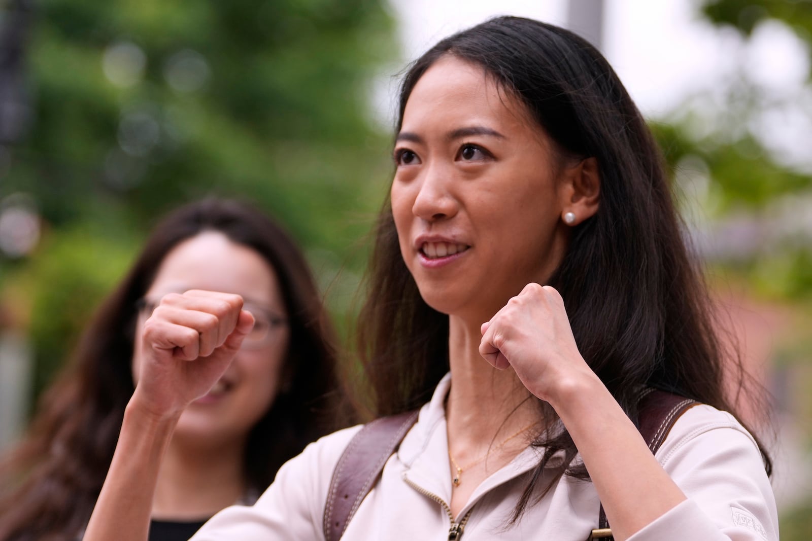 Yurong "Luanna" Jiang, who delivered a speech at her Harvard University commencement, raises her fists while talking with friends, Friday, May 30, 2025, in Cambridge, Mass. (AP Photo/Charles Krupa)