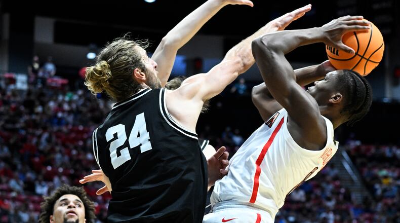 Arizona guard Bennedict Mathurin (0), right, shoots against the defense of Wright State guard Tim Finke (24) during the first half of a first-round NCAA college basketball tournament game, Friday, March 18, 2022, in San Diego. (AP Photo/Denis Poroy)