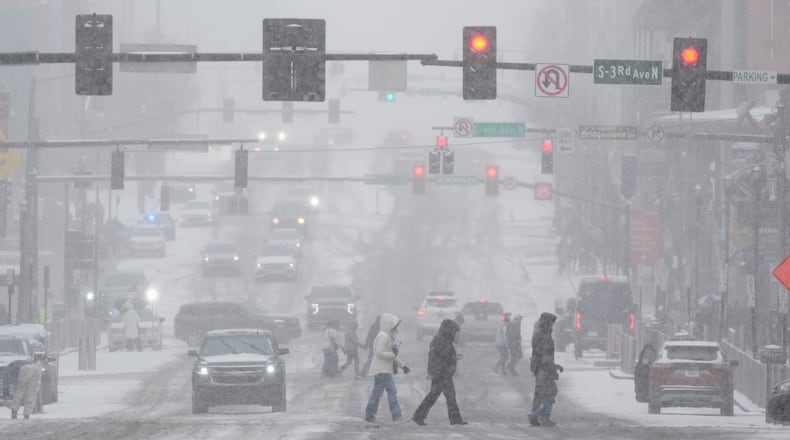 Pedestrians cross the street along Broadway during a winter storm Saturday, Jan. 24, 2026, in Nashville, Tenn. (AP Photo/George Walker IV)