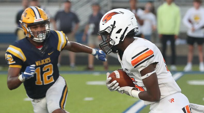 Beavercreek's Quentin Youngblood tries to avoid a tackle by Springfield's Teryon Holt during Friday night's game in Springfield. BILL LACKEY/STAFF