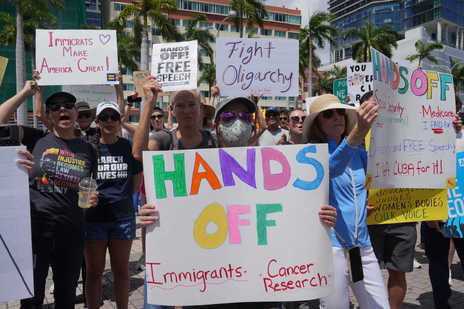 Protesters carry signs and chant slogans against the policies of President Donald Trump and Elon Musk Saturday, April 5, 2025, in Miami. (AP Photo/Marta Lavandier)