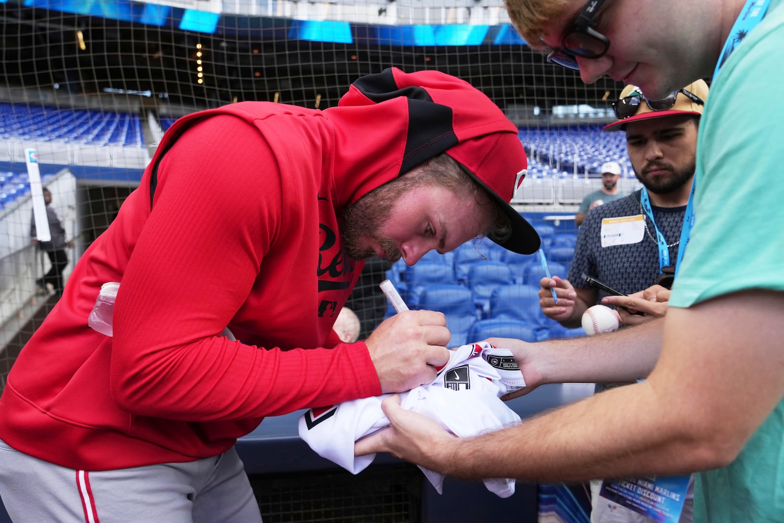 Cincinnati Reds' Gavin Lux, left, gives autographs before a baseball game against the Miami Marlins, Monday, April 21, 2025, in Miami. (AP Photo/Lynne Sladky)