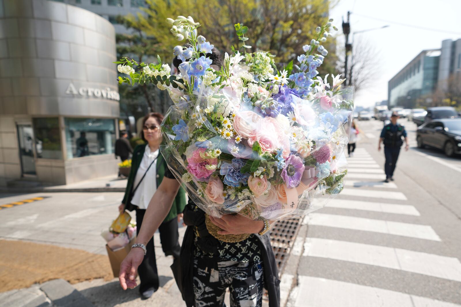 A supporter of recently removed South Korean President Yoon Suk Yeol carries flowers near Yoon's private residence in Seoul, South Korea, Friday, April 11, 2025. (AP Photo/Lee Jin-man)