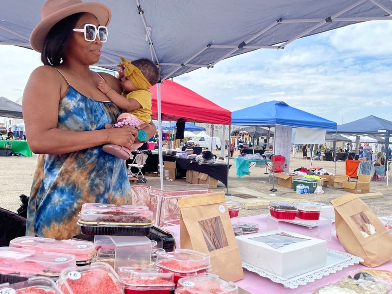 Jacquita Pridgen clutches her baby, Aris, as she talks to people at her bakery booth at the Fashion and Food Truck rally on Sunday in Dayton.