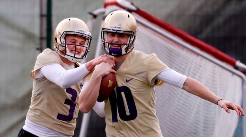 In this March 28, 2018, file photo, Washington's Jake Browning, left, tries to grab the ball from Jacob Eason during a drill for quarterbacks at the first practice of spring football for the NCAA college team, in Seattle. Eason knew his opportunity at Georgia was going to be limited if he remained with the Bulldogs. So he transferred home to Washington, even if it means he has to spend a year as a spectator. (AP Photo/Elaine Thompson, File)