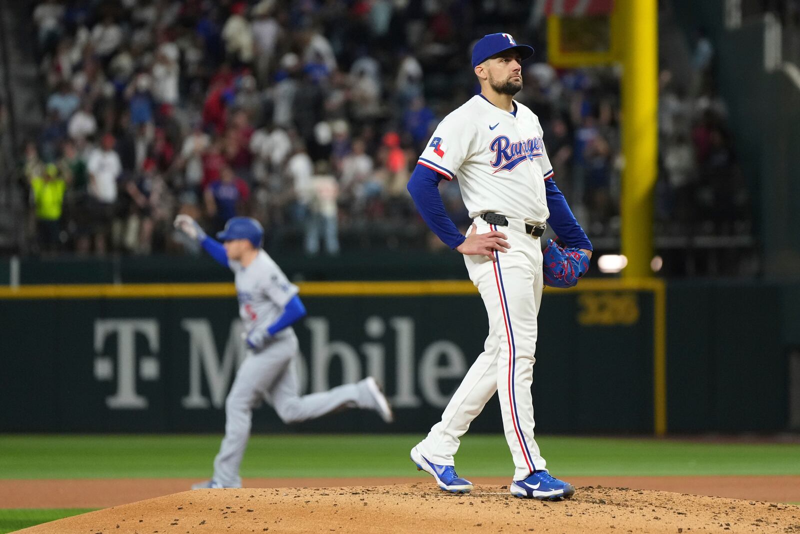 Texas Rangers starting pitcher Nathan Eovaldi stands on the mound after giving up a two run home run to Los Angeles Dodgers' Freddie Freeman, rear, that scored Mookie Betts during the fourth inning of a baseball game Saturday, April 19, 2025, in Arlington, Texas. (AP Photo/Jeffrey McWhorter)