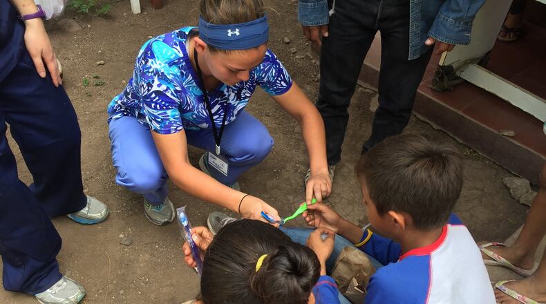 University of Dayton soccer player Sarah Byrne working on a medical brigade with two small Nicaraguan kids on personal and dental hygiene. CONTRIBUTED