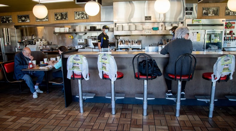 Kim Kaseta (L) waits for her pattie melt while sitting at the counter at the Waffle House in Brookhaven on Monday, when Georgia restaurants were allowed to have customers dine in again. The bags covering the chairs marked where customers weren’t allowed to sit in order to keep some social distancing. STEVE SCHAEFER / SPECIAL TO THE AJC