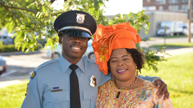 Newly graduated Dayton Police officer Bibebibyo “Bibe” Seko and his mom Sela (orange head wrap) surrounded by their family at Bibe’s graduation. (Photo by Gary Laughlin)