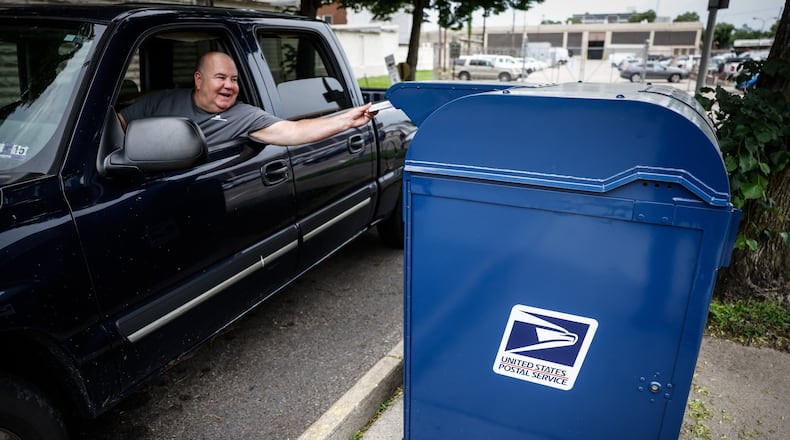 A resident pushes mail into the mailbox outside the postal office on Fifth St. in Dayton on Wednesday afternoon May 18, 2022. A postal service key that unlocks all Dayton-area mailboxes was stolen recently, police records show. JIM NOELKER/STAFF