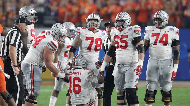 Ohio State offensive lineman Billy Price, left, helps up J.T. Barrett in the first half Saturday in the Fiesta Bowl. David Jablonski/Staff