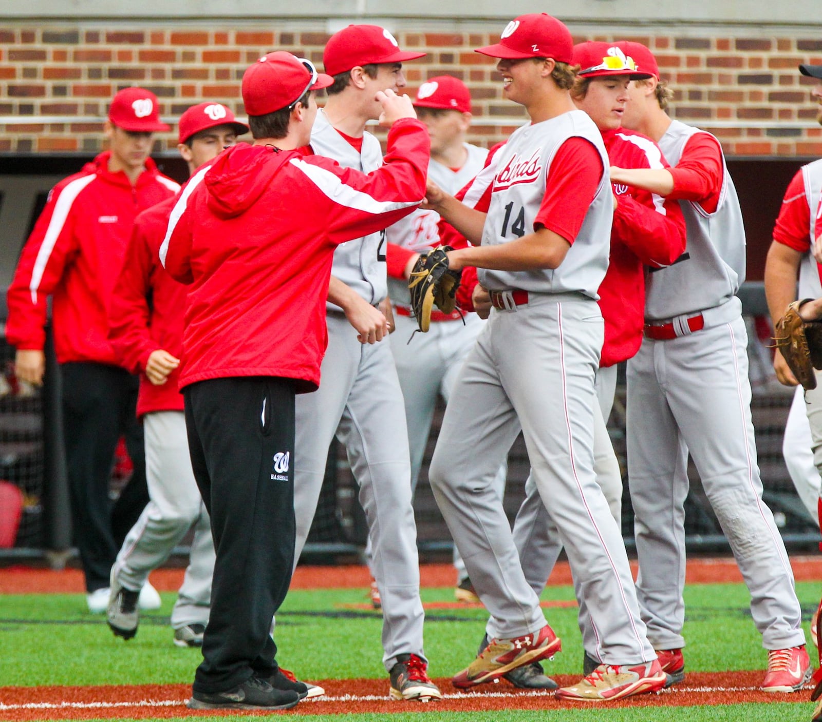 Teammates celebrate with Lakota West pitcher Jacob Kates (14) after their Division I regional semifinal victory over Centerville on Thursday at the University of Cincinnati’s Marge Schott Stadium. GREG LYNCH/STAFF