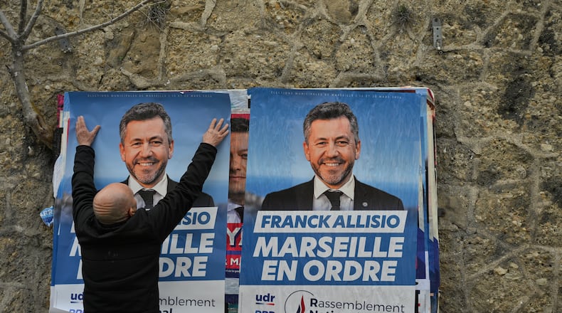 A supporter of far-right candidate Franck Allisio, pastes an electoral poster ahead of the first round of the mayoral elections, in Marseille, south of France, Friday, March 6, 2026. (AP Photo/Philippe Magoni)