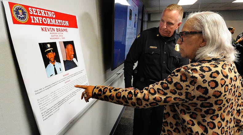 Rosemary Brame, mother of Dayton police officer Kevin Brame who was gunned down in November 1999, points to an FBI poster with Maj. Brian Johns of the Dayton Police Department after a Thursday, April 11, 2024, press conference at the Dayton Safety building. MARSHALL GORBY\STAFF