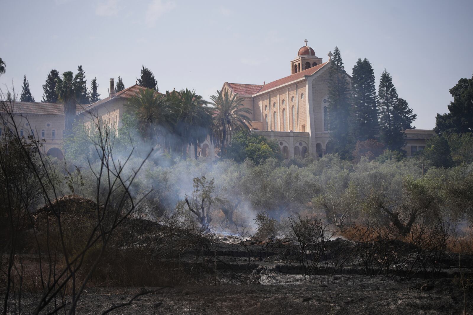 Fire smolders outside of the Roman Catholic Trappist monastery where Israeli fire crew is battling a wild fire in Latrun, Israel, outside of Jerusalem Thursday, May 1, 2025. (AP Photo/Ohad Zwigenberg)