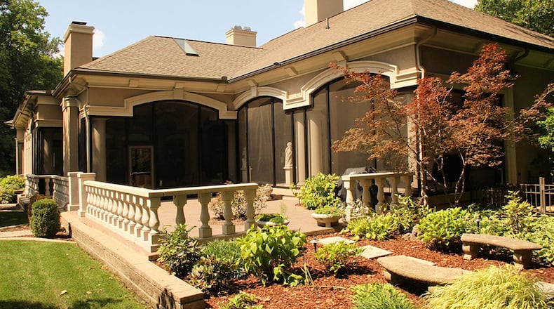 Arched windows and tall columns embellish the screened porches and verandas at the back of the home, which overlooks Hole’s Creek and a naturally wooded hillside.