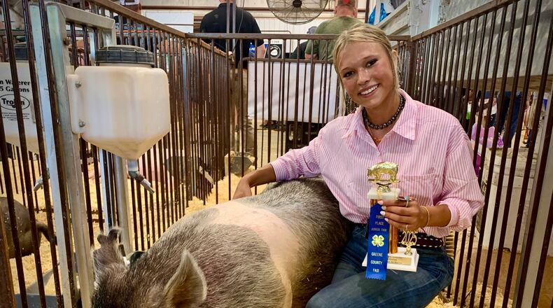 Sydnee Hawkins, 19, smiles with her class-winning hog at the Greene County Fair, Tuesday July 29, 2025. LONDON BISHOP/STAFF