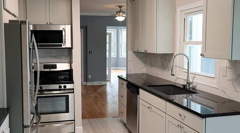 As an addition to the original floor plan design, the kitchen has been completely renovated. The new floor plan design allows for a breakfast room with backyard patio access and double corner windows. The galley-style kitchen has gray cabinets with light granite countertops. A large sink is below a window and ceramic-tile creates a backsplash. Counter space allows for a coffee station and buffet counter near the breakfast room. Contributed photo