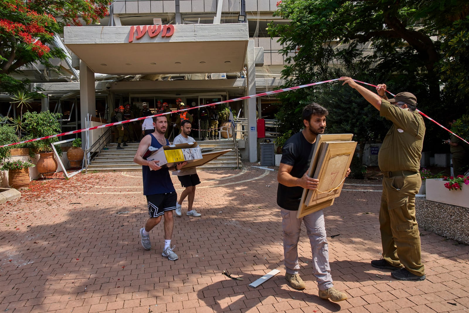 People recover items from a building damaged in an Iranian missile strike in Tel Aviv, Israel, Sunday, June 22, 2025. (AP Photo/Bernat Armangue)