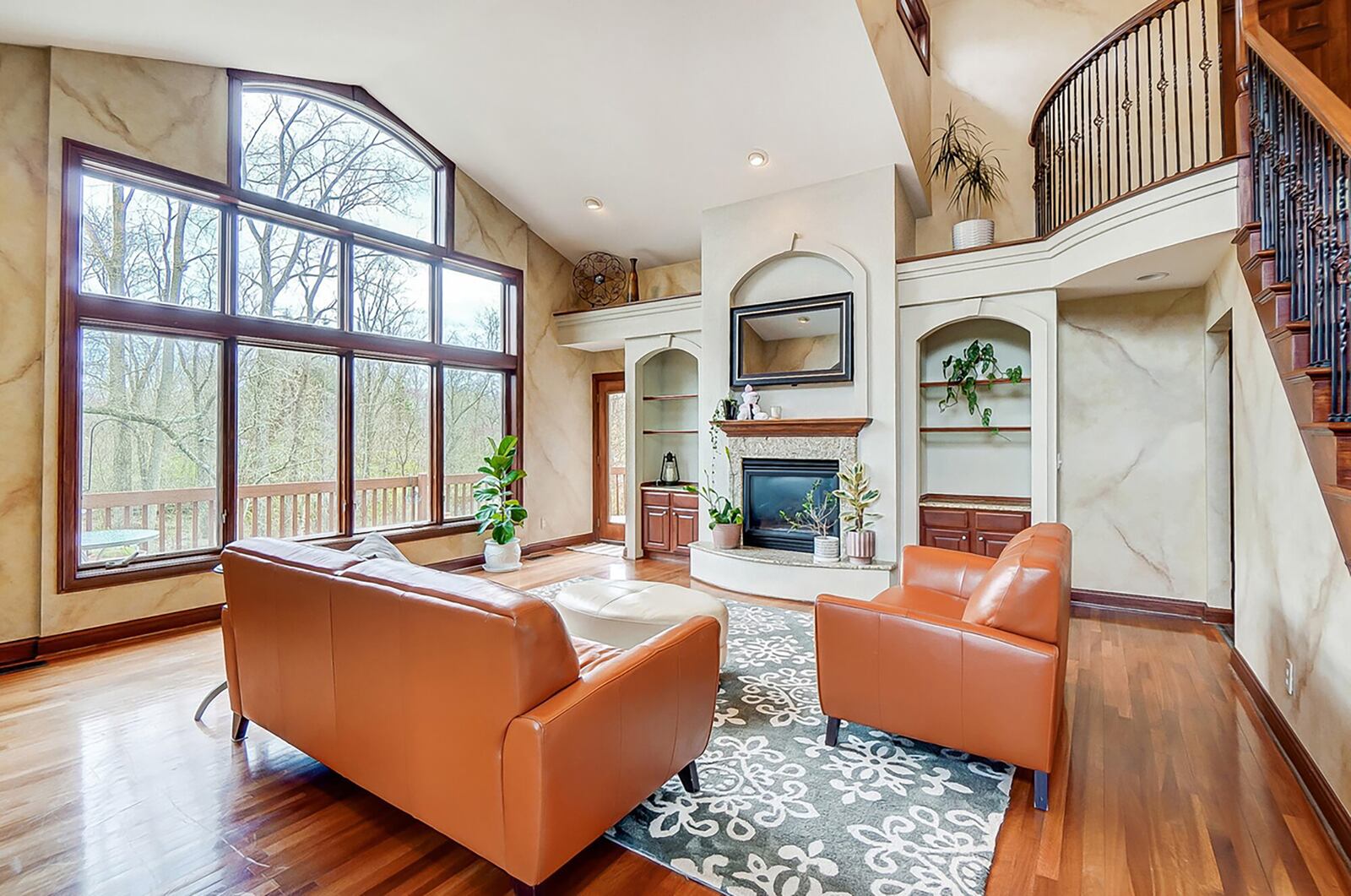 The two story great room has a gas fireplace flanked by two built in bookcase cabinets and wood flooring.