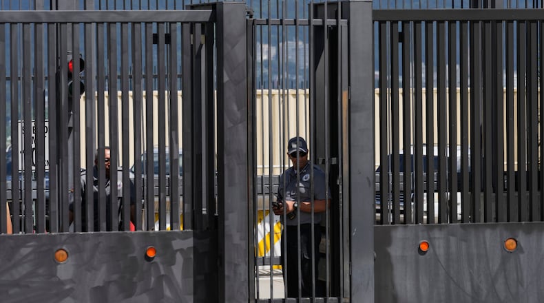 Security officers stand behind the main gate of the United States embassy in Caracas, Venezuela, Monday, Oct. 27, 2025. (AP Photo/Ariana Cubillos)