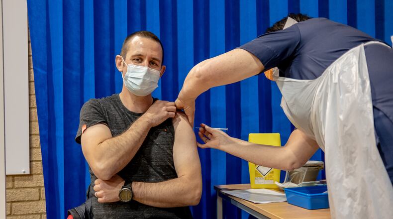 Chris Hingston, an intensive care unit doctor, is given the Pfizer-BioNTech COVID-19 vaccine in Cardiff, Wales, on Tuesday, Dec. 8, 2020. Great Britain’s National Health Service delivered its first shots of the vaccine on Tuesday, opening a mass vaccination campaign with little precedent in modern medicine and making Britons the first people in the world to receive a clinically authorized, fully tested vaccine. (Andrew Testa/The New York Times)