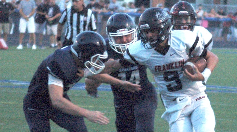 Franklin quarterback Braden Woods tries to escape a pair of Valley View defenders during first-quarter action Friday night at Barker Field in Germantown. CONTRIBUTED PHOTO BY JOHN CUMMINGS