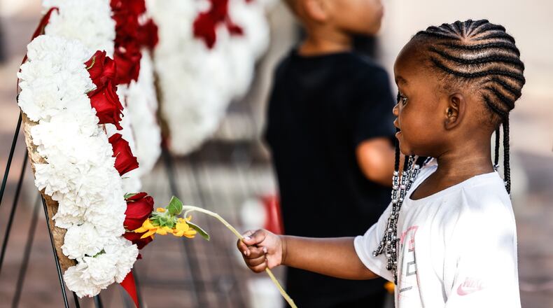 Leilani Reid touches a flower to one of the nine wreaths for each of the Oregon District victims during a remembrance in honor of the second anniversary of the Aug. 4, 2019, mass shooting in Dayton. Jim Noelker/Staff