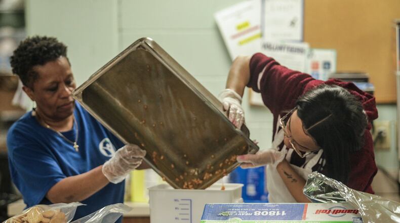 Cynthia Collier, left and Angel Gibson work in the kitchen at St. Vincent De Paul Society on Apple Street in Dayton Friday morning. JIM NOELKER/STAFF